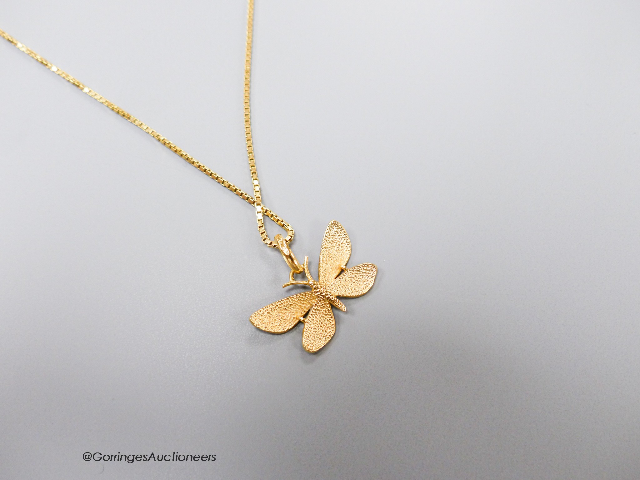 A three colour enamelled butterfly pendant, 23mm (enamel a.f.), on an Italian 750 yellow metal chain, 49cm, 5.2 grams.